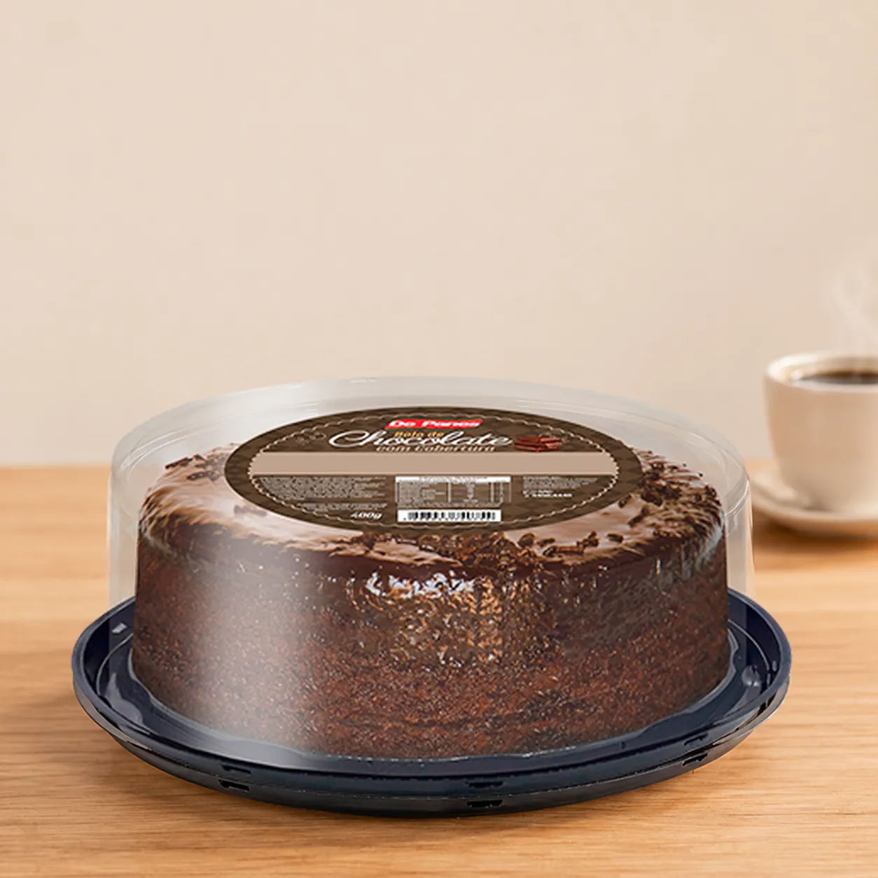 Bolo de chocolate De Panes na embalagem, sobre mesa de madeira com xícara de café